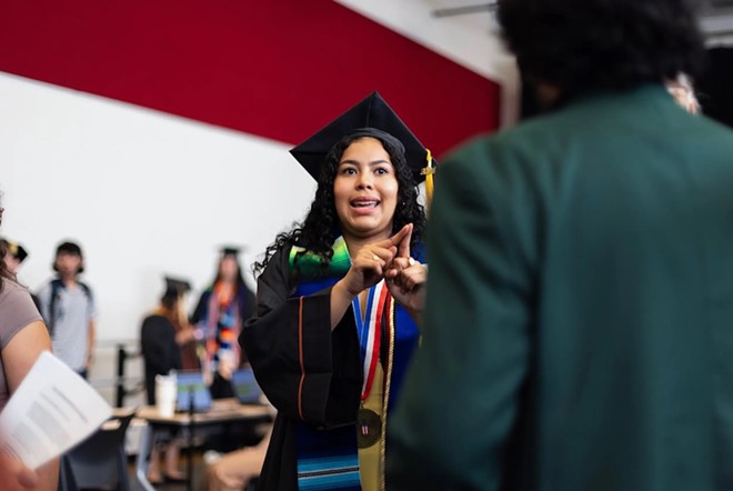 Liany Serrano Oviedo assigns roles to organizers prior to the ceremony as she was helping guide and organize the graduates at the ceremony. “This really, really is a big deal because they're joining a cohort of Latinos who pretty much faced all odds to be able to get into higher education and stay there,” she said. - Texas Tribune / Maria Crane