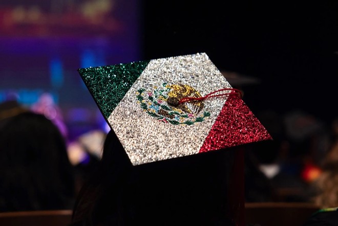 A decorated cap of the Mexico flag done in rhinestones sits on top of a graduate’s head during the ceremony. For some students and faculty, celebrating the accomplishments of Latinx students is a critical recognition of the hard road that they journeyed on to get their degree. Credit: - Texas Tribune / Maria Crane