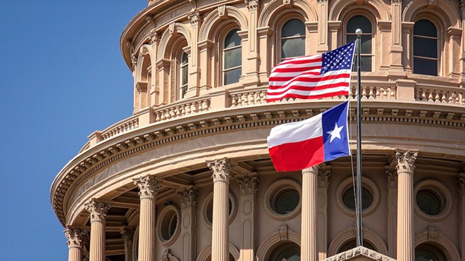 The Texas and United States flag billow in the wind at the Texas State Capitol in Austin. - Shutterstock / CrackerClips Stock Media