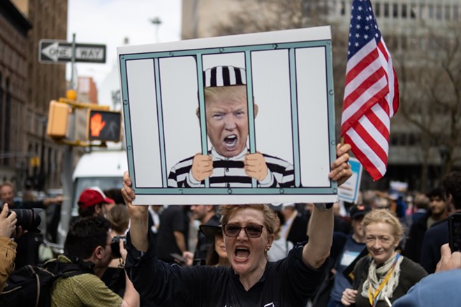 A woman protests outside of a New York City courthouse ahead of former President Donald Trump's indictment in April 2023. - Shutterstock / James Andrews1