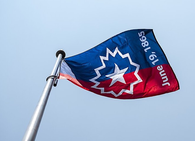 A Juneteenth flag waves in the wind during a 2023 ceremony. - Wikimedia Commons / NASA / Keegan Barber