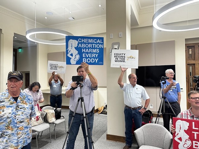 Anti-abortion protesters hold up signs at Monday's press conference. - Michael Karlis