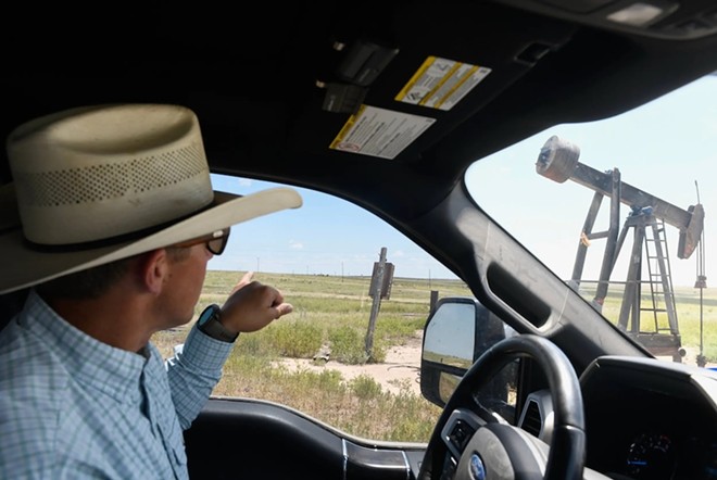 Craig Cowden points to a pump jack on his Breezy Point Ranch in Pampa on July 7. Cowden said he often spots problems with oilfield electrical equipment such as a pumpjack with faulty wiring or a power line lying on dead grass. - Texas Tribune / Annie Rice