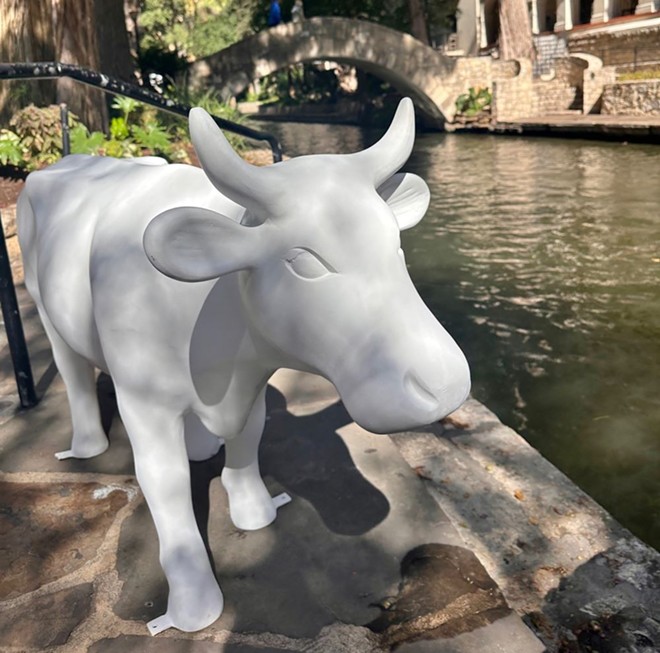 An unpainted CowParade sculpture stands on the San Antonio River Walk.