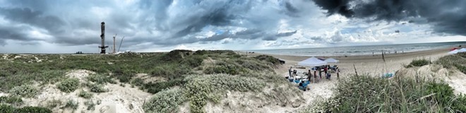 A panoramic view of Boca Chica Beach with the SpaceX launch facility to the left and members of the ENTRE Film Center, a local film center and regional archive, set up near the dunes on the right. - Texas Tribune / Ben Lowry