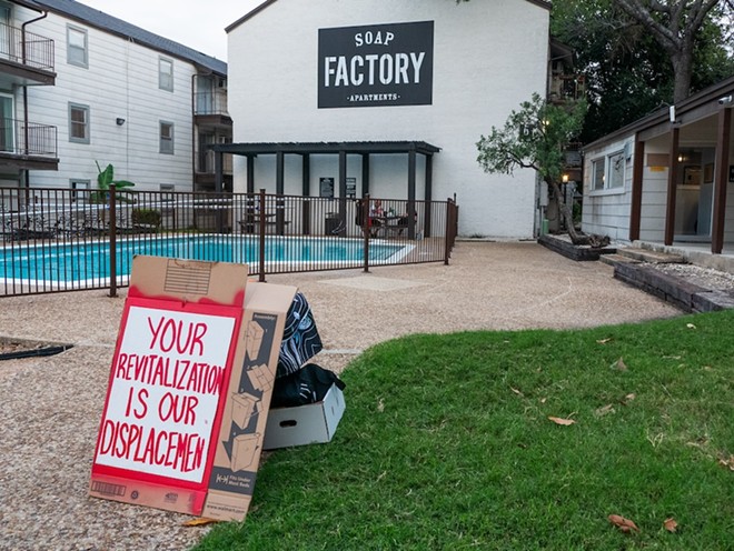 An anti-displacement sign made by tenants stands near the Soap Factory Apartments' pool on Monday. - Adam Doe