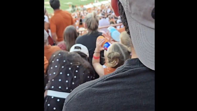 A child chugs from a red and blue tallboy during the Texas Longhorns football game on Saturday. - TikTok / @trish.prell