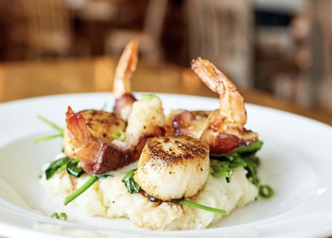 Seared Georges Bank scallops with applewood bacon-wrapped shrimp is one of the entrees served at Fish City Grill locations. - Instagram / fishcitygrill