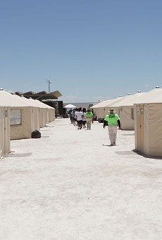 Staff and detainees walk between the tents inside the Tornillo, Texas, detention center.