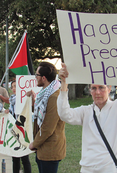 Protestors hold up signs and banners outside of Pastor John Hagee's Cornerstone Church.