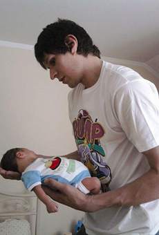 Boban Marjanović holding a baby with his enormous hands.
