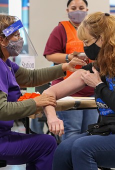 A woman receives her COVID-19 vaccination at the Alamodome.