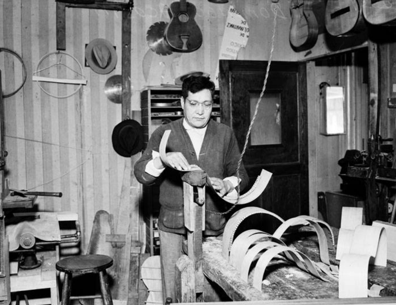 In this 1937 photo shows Domingo Acosta working on a guitar at his family's guitar business. He's using a special homemade device to work on the instrument.